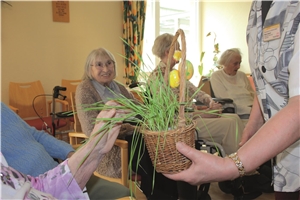 Bewohnerin fasst Weizenhalme im Gottesdienst an