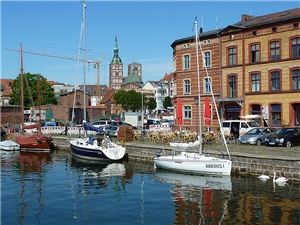 Blick auf die Altstadt an einem sonnigen Sommertag mit Wasser und Booten im Vordergrund.