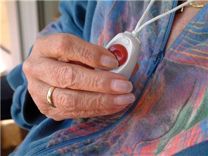Hausnotruf Seniorin hält den Notrufknopf, den sie um den Hals trägt