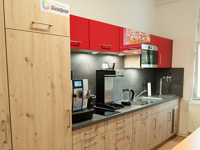 Blick in eine Küche mit rotlackierten Fronten und einer holzfarbenen Arbeitsplatte