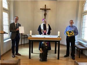 Herr Klapper mit Blumenstrauß und Urkunde, Weihbischof Dr. Hauke und Vorstand Mark Keuthen