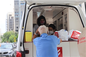 ein Minibus mit Caritas-Mitarbeitern, welche Medikamente verteilen