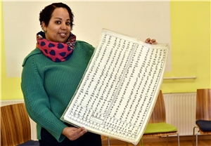 Eine Frau hält ein Plakat für den Unterricht der amharischen Sprache in die Kamera.