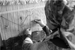 schwarz-weiß Foto einer arabischen Frau beim Weben eines Teppiches