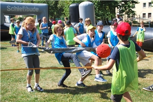 Mehrere Kinder stehen an einem Seil und versuchen und spielen mit einem Ball Tipp-Kick