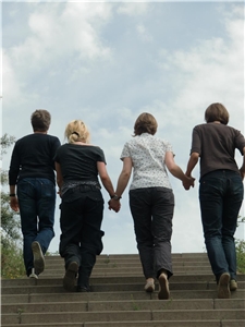 Vier Frauen gehen Hand in Hand eine Treppe hoch
