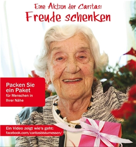 Weihnachtspaketaktion Eine ältere Dame hält ein Geschenk im Arm und lacht fröhlich