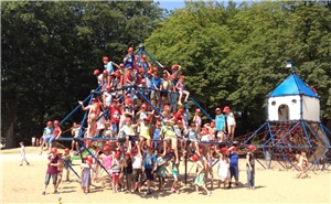 Ganz viele Kinder hängen in einem Klettergerüst auf dem Spielplatz