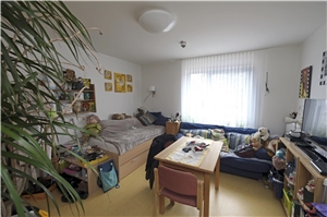 Das Zimmer einer Bewohnerin mit Bett, Tisch und St�hlen sowie einer Couch