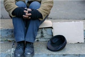 Ein Mann, von dem Mann nur die Beine und die Hände sieht, sitzt auf der Straße