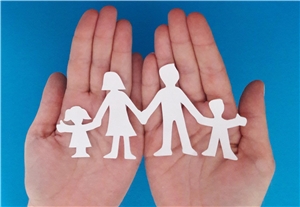 Hände halten eine aus Papier ausgeschnittene Familie