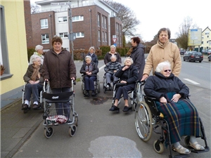 Ehrenamtliche begleiten Senioren im Rollstuhl