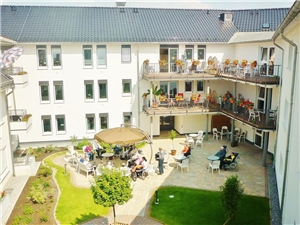 Der Innenhof des  St. Engelbert Seniorenzentrum bietet viele Sitzplätze. Gerahmt ist die Anlage mit Blumenbeeten und Rasen.