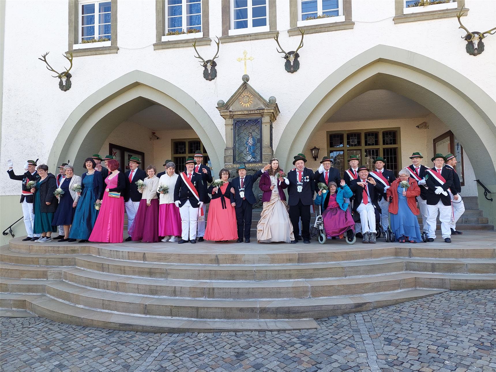 Auf einer großen Treppe stehen Frauen in Festkleidern und Männer in Anzügen von einem Schützenverein.