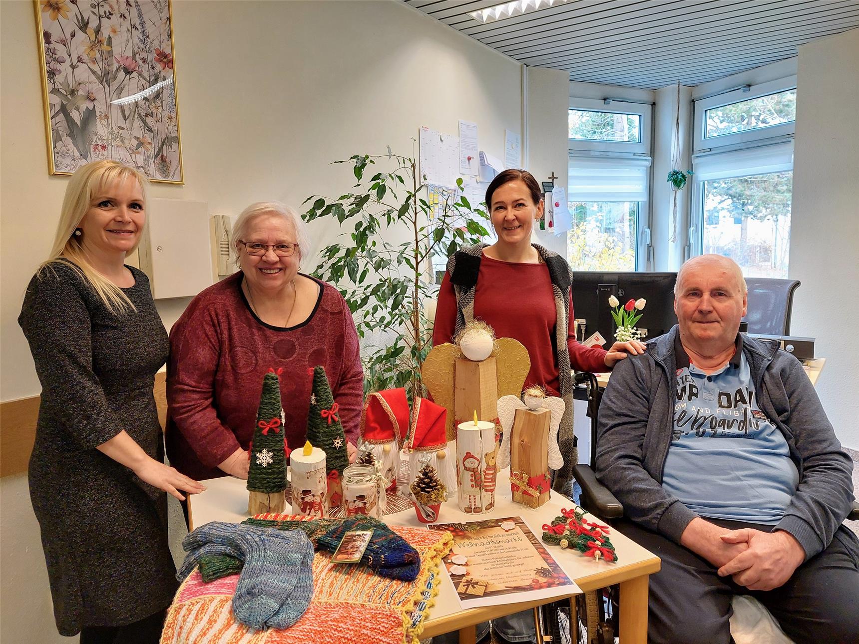 Zwei Gäste und zwei Mitarbeiterinnen des Caritas Tagespflegehaus zeigen ihre selbstgemachten Dekorationen aus Wolle und Holz für den Weihnachtsmarkt.