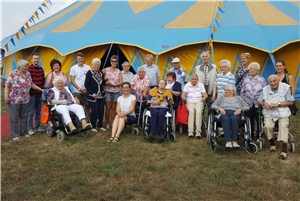 25 Menschen mit und ohne Behinderung vor einem Zirkuszelt