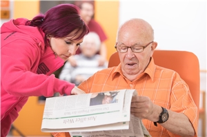 Bewohner und Pflegekraft bei Zeitungsschau Bewohner und Pflegekraft bei Zeitungsschau