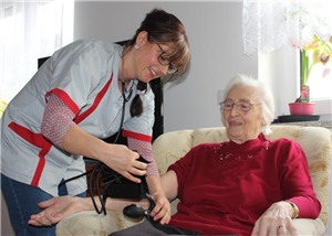 Pflegefachkraft möchte bei Seniorin Blutdruck messen