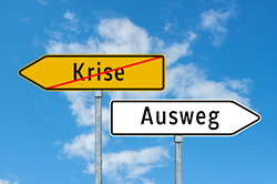 Ausweg in Sicht: Wege aus Krisensituationen (© animaflora / Fotolia) Foto mit zwei Straßenwegweisern: Eines mit dem durchgestrichenen Text Krise und eines in die Gegenrichtung zeigendes mit dem Text Ausweg