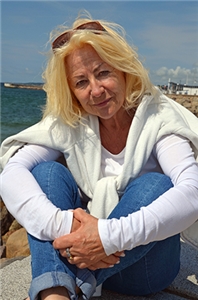 Portrait einer Frau, im Hintergrund sind Meer und Küste