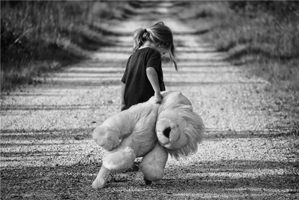 Kind mit Stofftier auf einsamem Weg