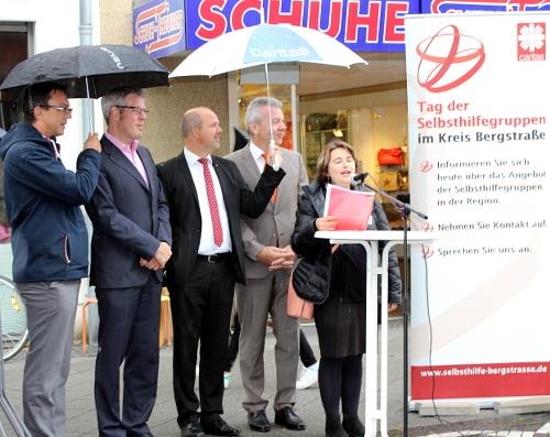Menschengruppe bei Regen, Frau am Mikrofonpult