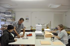 Zwei Mitarbeiterinnen und ein Anleiter bei der Arbeit in einer Druckerei