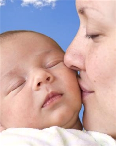 Eine Frau küsst einen schlafenden Säugling