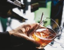 Eine Männerhand hält ein Whiskyglas und eine Zigarette