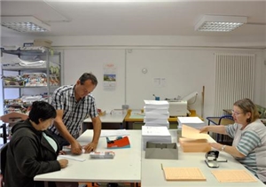 Spenden-Projekt 1 Zwei Mitarbeiterinnen und ein Anleiter bei der Arbeit in einer Druckerei