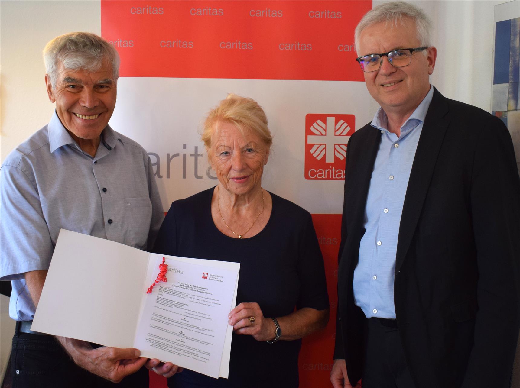 Anita und Sieghard Berneis präsentieren den Vertrag ihres Stiftungsfonds mit der Caritas-Stiftung. Rechts: Der Vorstandsvorsitzende der Caritas-Stiftung Caritasdirektor Matthias Mitzscherlich.