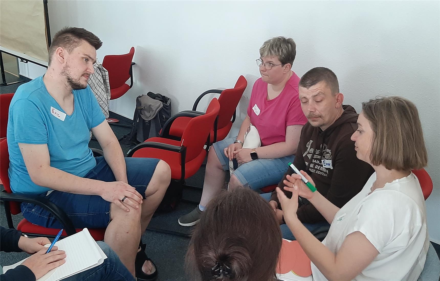 Auf dem Bild sind mehrere Personen in einer Gruppenarbeit zu sehen.