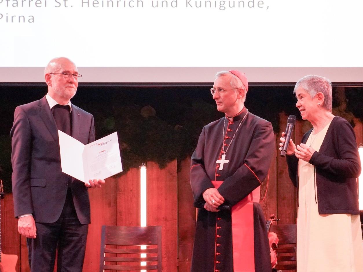 2. Preis für Pfarrer Vinzenz Brendler und die Pfarrei St. Heinrich und Kunigunde - Durch ihren Einsatz konnte die Ausstellung „Es ist nicht leise in meinem Kopf“ des Flüchtlingsunterstützerkreises Schwarzenberg im Herbst 2024 doch noch eröffnet und gezeigt werden.