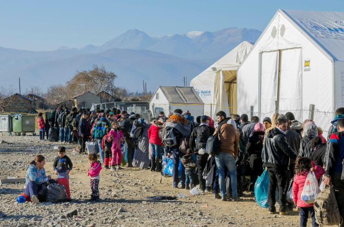 Geflüchtete Menschen stehen in einem Aufnahmelager in der Schlange.