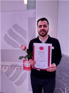 Mohamad Dadou, Gewinner des Elisabethpreises 2023, hält Urkunde und Rose in den Händen.