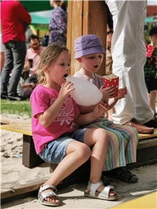 Zwei Mädchen sitzen am Sandkaszen und Essen Popcorn und Zuckwerwatte.