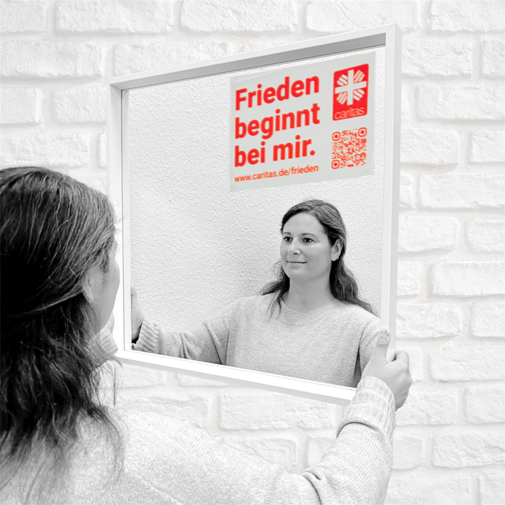 Aline steht vorm Spiegel mit aufgeklebtem Motto und lächelt