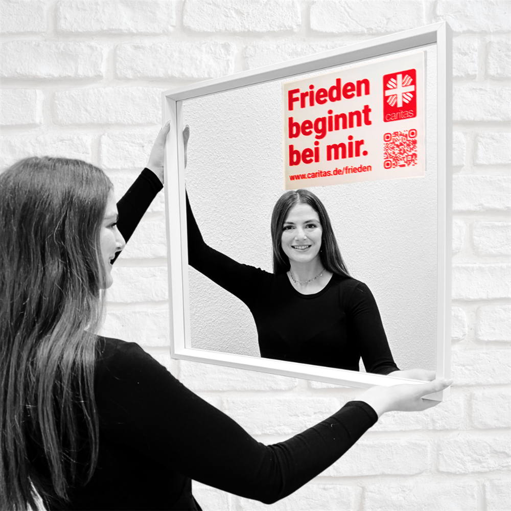 Deborah steht vorm Spiegel mit aufgeklebtem Motto und lächelt