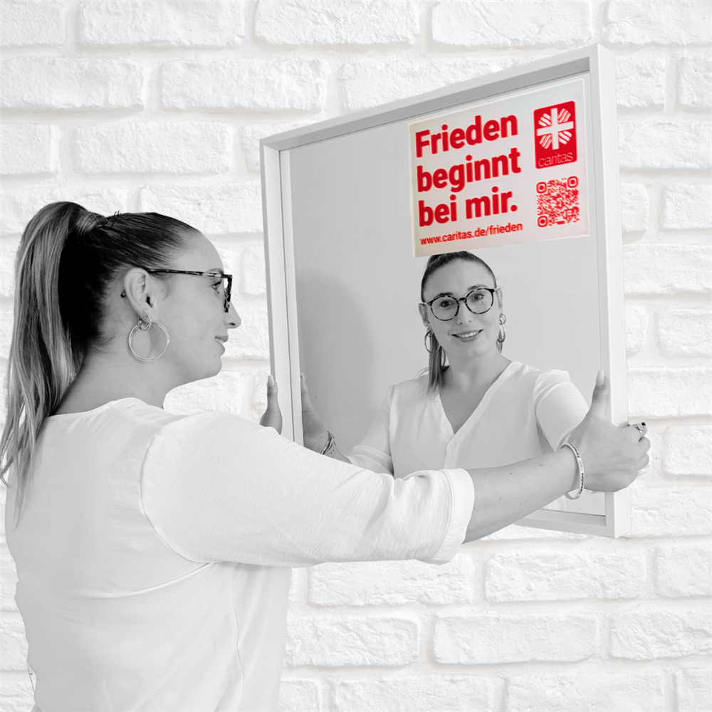 Elaine steht vorm Spiegel mit aufgeklebtem Motto und lächelt