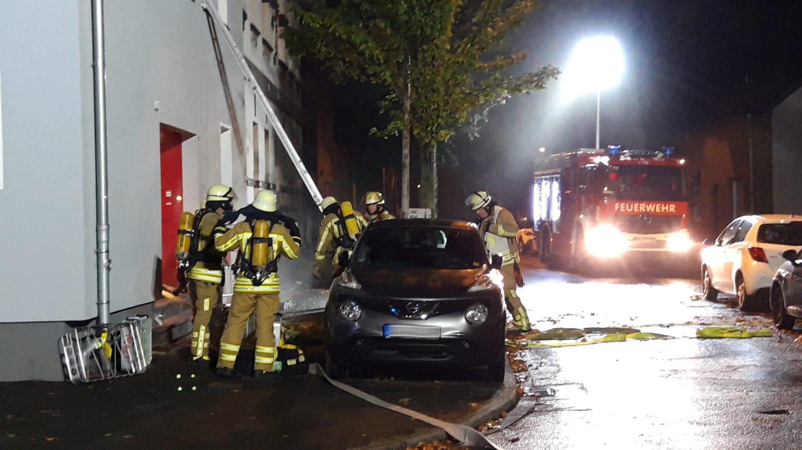 Links im Bild einige Einsatzkräfte vor der Haustüre, rechts auf der Straße ein Feuerwehrwagen