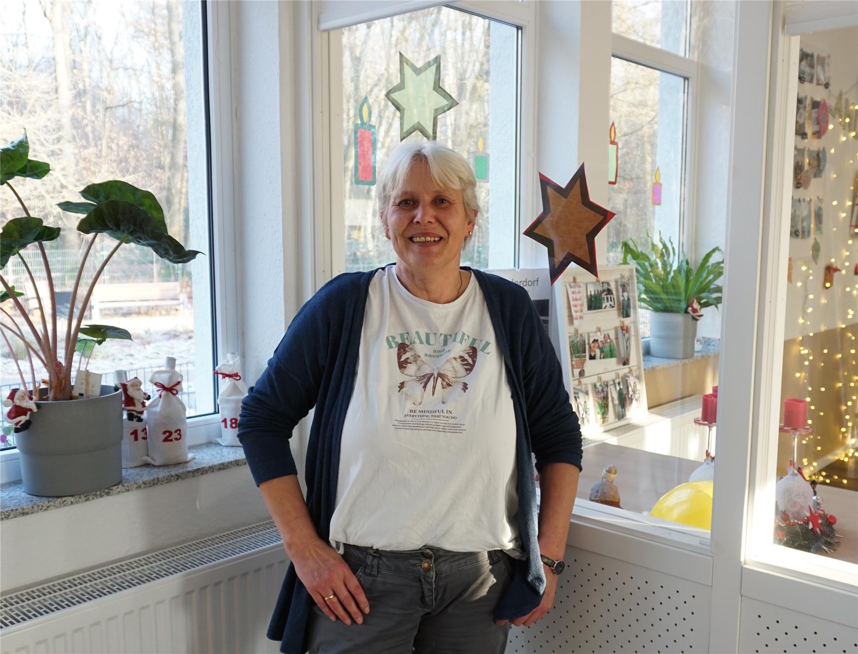 Gerda Germes steht vor weihnachtlich geschmückten Fensterfronten der Tagespflege
