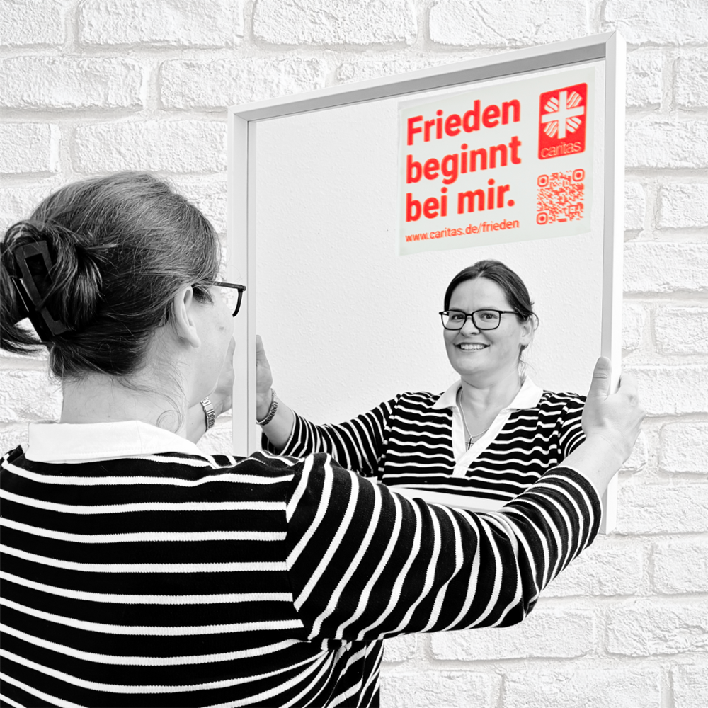 Frau Schröder steht vorm Spiegel mit aufgeklebtem Motto und lächelt