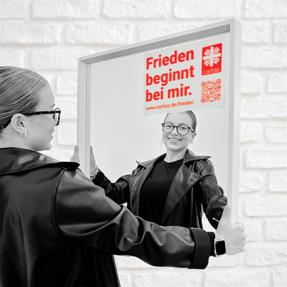 Leoni steht vorm Spiegel mit aufgeklebtem Motto und lächelt