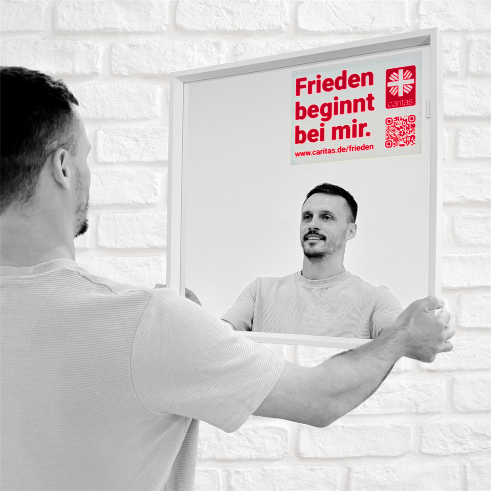 Marcel steht vorm Spiegel mit aufgeklebtem Motto und lächelt