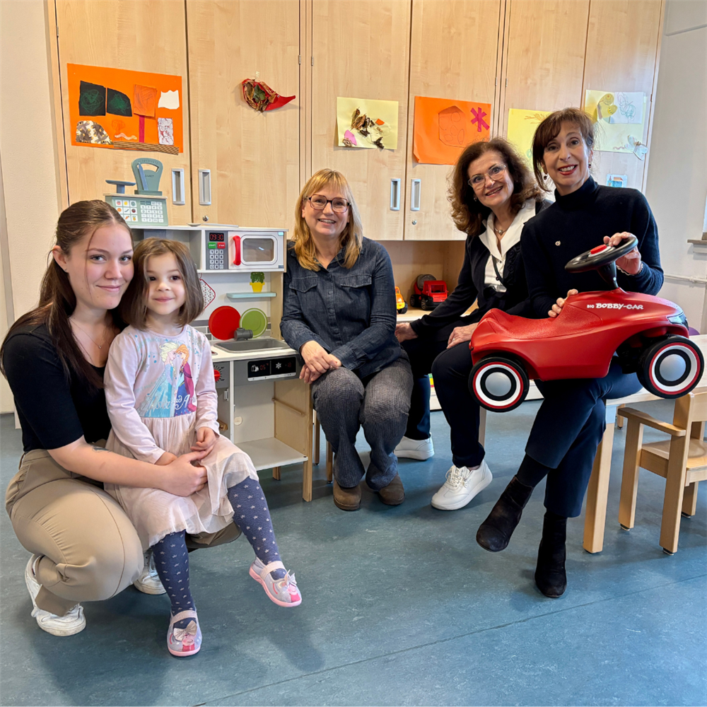 Gruppenbild v.l.n.r.: Mitarbeiterin mit kleiner Bewohnerin auf dem Schoß, Einrichtungsleitung, zwei Vereinsmitglieder mit Bobby Car