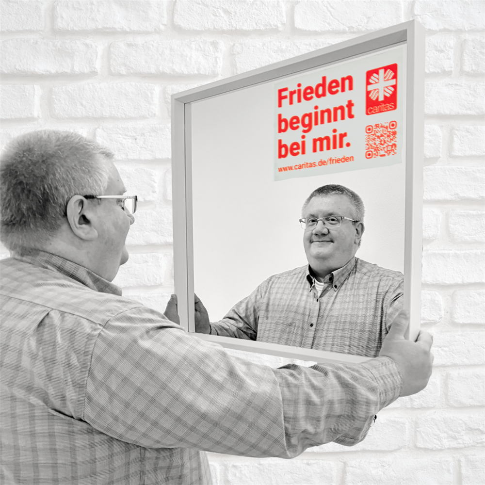 Stefan steht vorm Spiegel mit aufgeklebtem Motto und lächelt