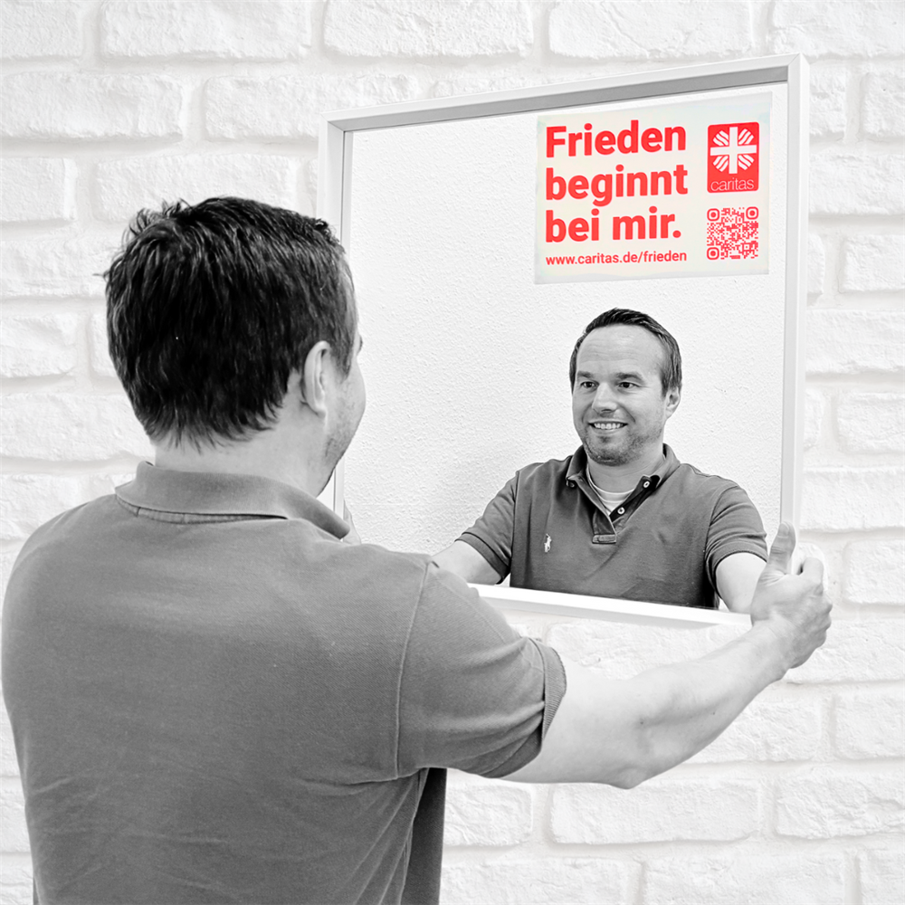 Stephan steht vorm Spiegel mit aufgeklebtem Motto und lächelt