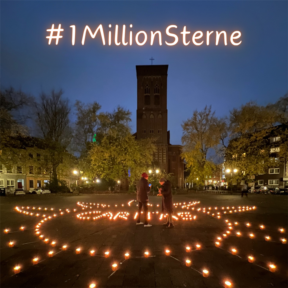 Bei Dämmerung auf dem Dellplatz stehen zwei Personen inmitten von vielen brennenden Teelichtern