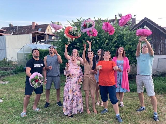 Das Bild zeigt unsere Auszubildenden mit ihren Anleitungen, während Sie die Blumensträuße in die Luft werfen.