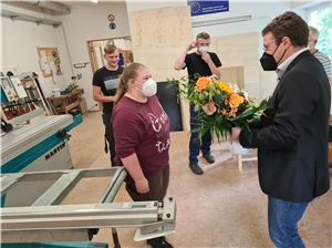 Michelle (li.) bedankt sich mit einem Blumengruß bei MdL Max Gibis. Dahinter Sebastian und Johannes.Foto: © cmg | Caritas FRG. 